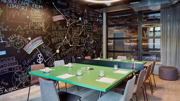 Ein moderner Konferenzraum mit einem grünen Tisch, weißen Stühlen und einer Tafel mit motivierenden Sprüchen und Kritzeleien.