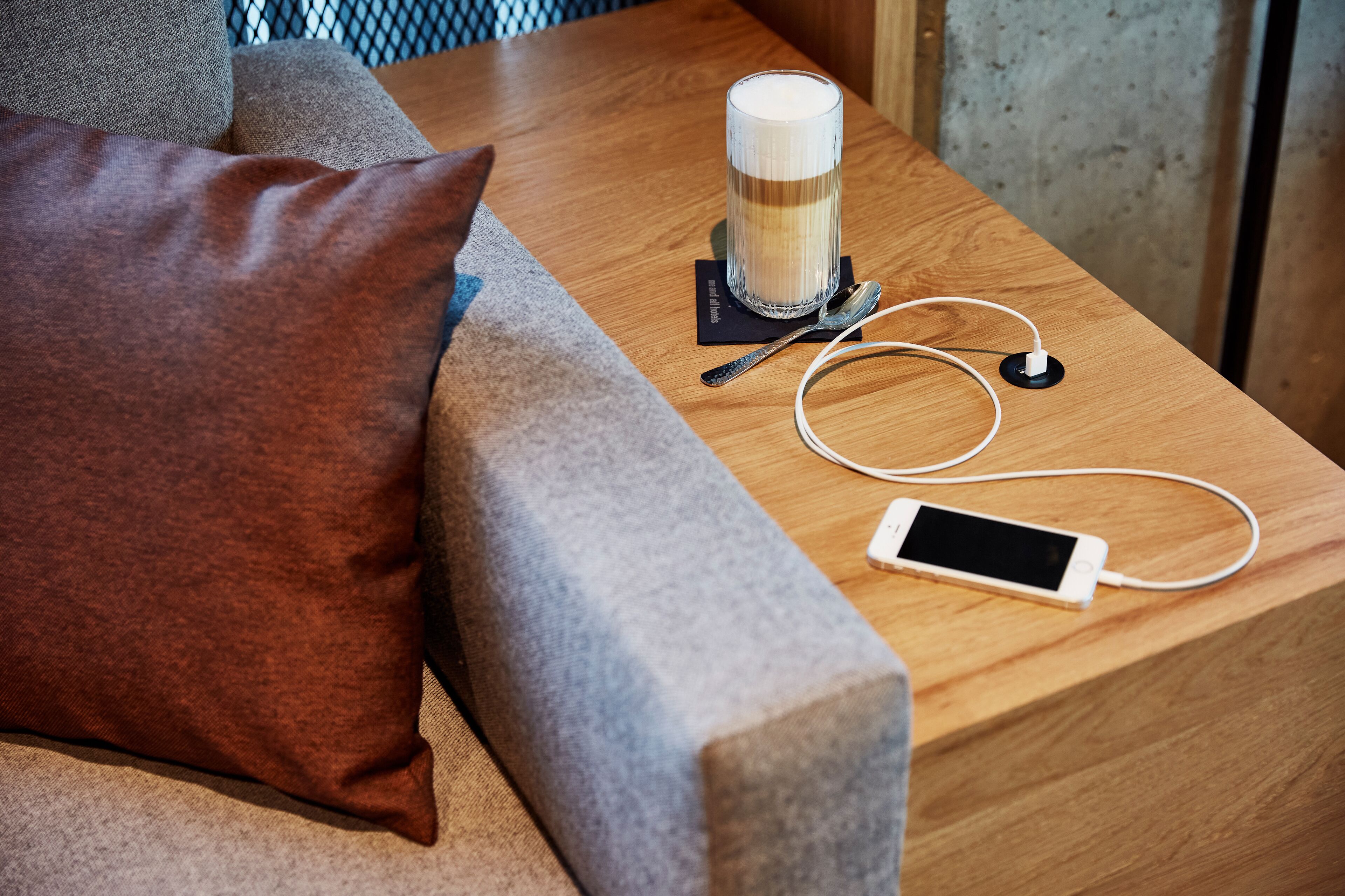 Una mesa de madera con un teléfono inteligente, auriculares y una taza de café.