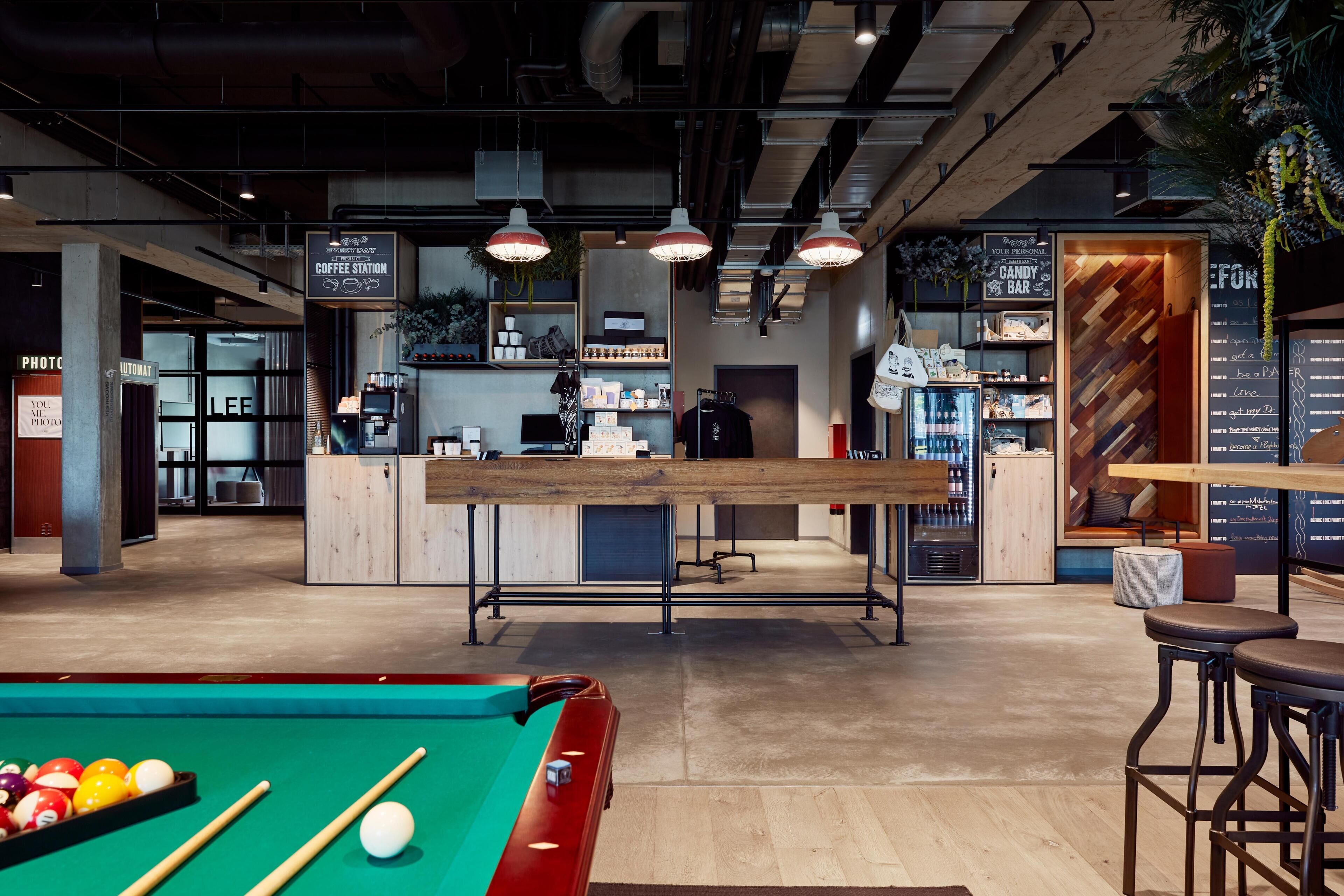 A billiards table, a coffee station, and a bar area with shelves and a menu.