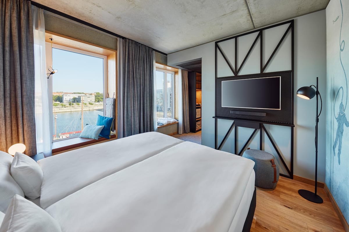 Une chambre d’hôtel avec un grand lit, un téléviseur à écran plat, un bureau et une vue sur la ville.