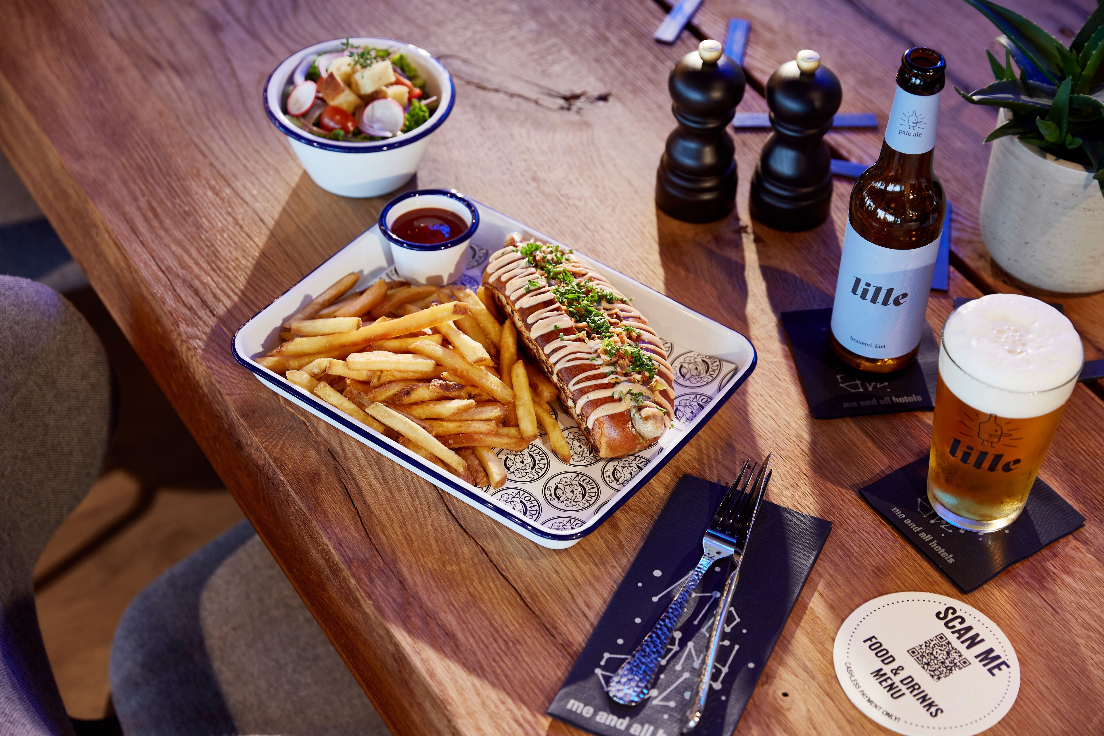 A table with a plate of food, a bottle of beer, and a QR code menu.