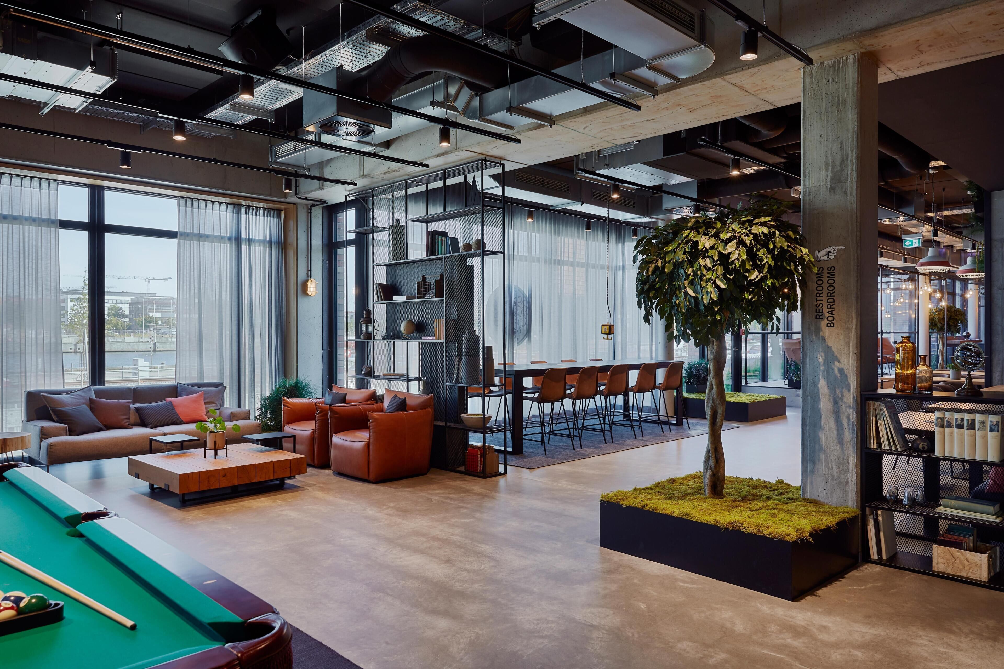 A modern lounge area with a pool table, sofas, a bar, and a bookshelf.