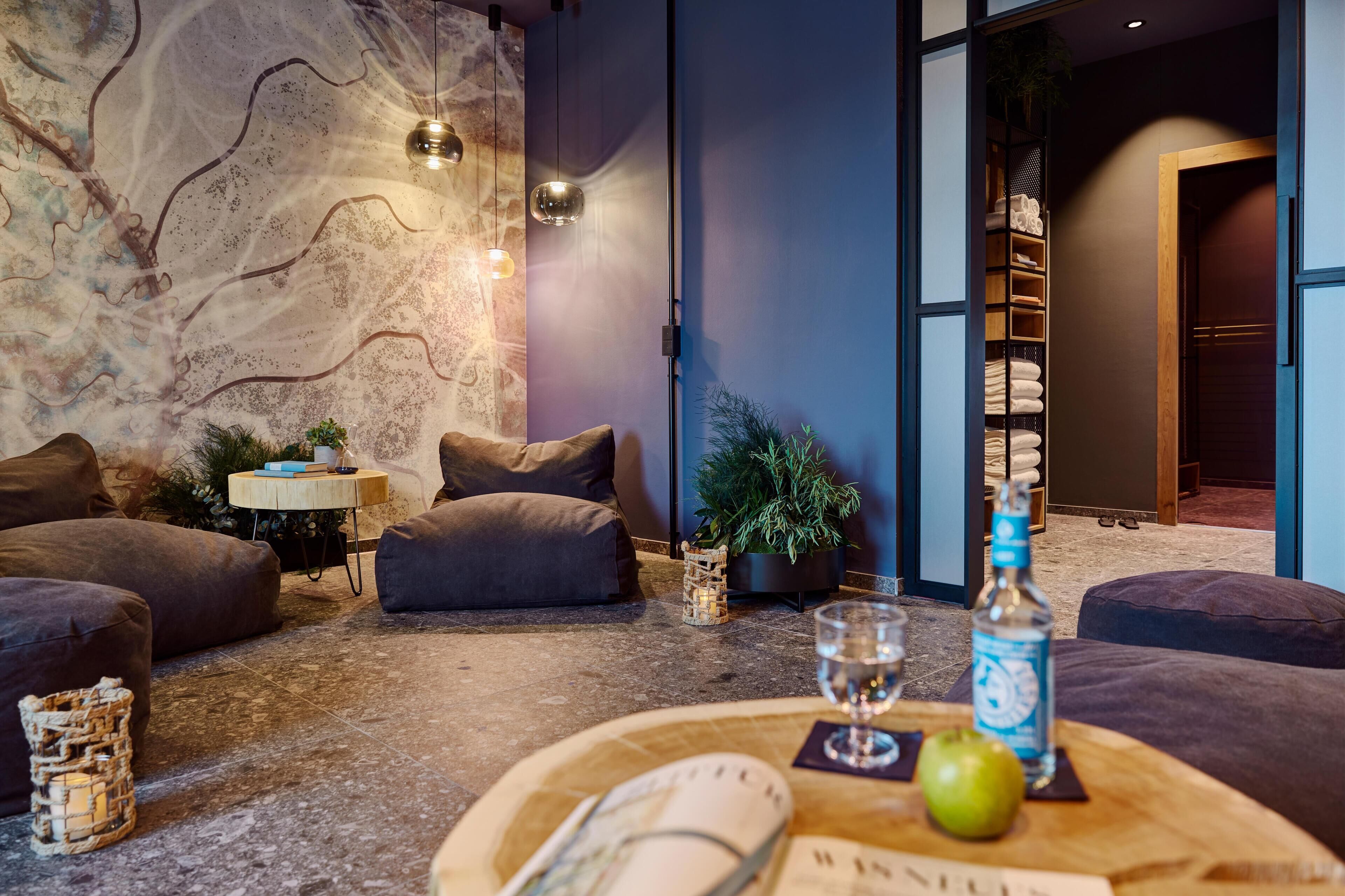 Ein modernes Wohnzimmer mit Steinwand, einer Sofagarnitur, einem kleinen Tisch mit Flasche und Glas sowie einer Pflanze.