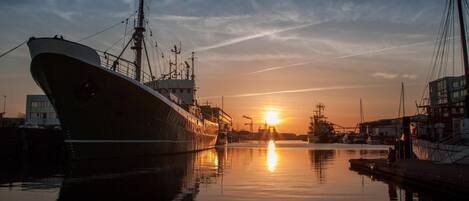 A large ship docked at a harbor with a sunset in the background.