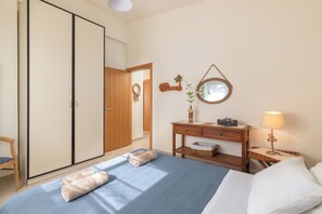 Une chambre d’hôtel avec un lit, un bureau doté d’une lampe, une armoire et un miroir au mur.