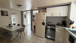 Kompakti keittiö, jossa on ruokailutila, valkoiset kaapit, liesi ja jääkaappi.