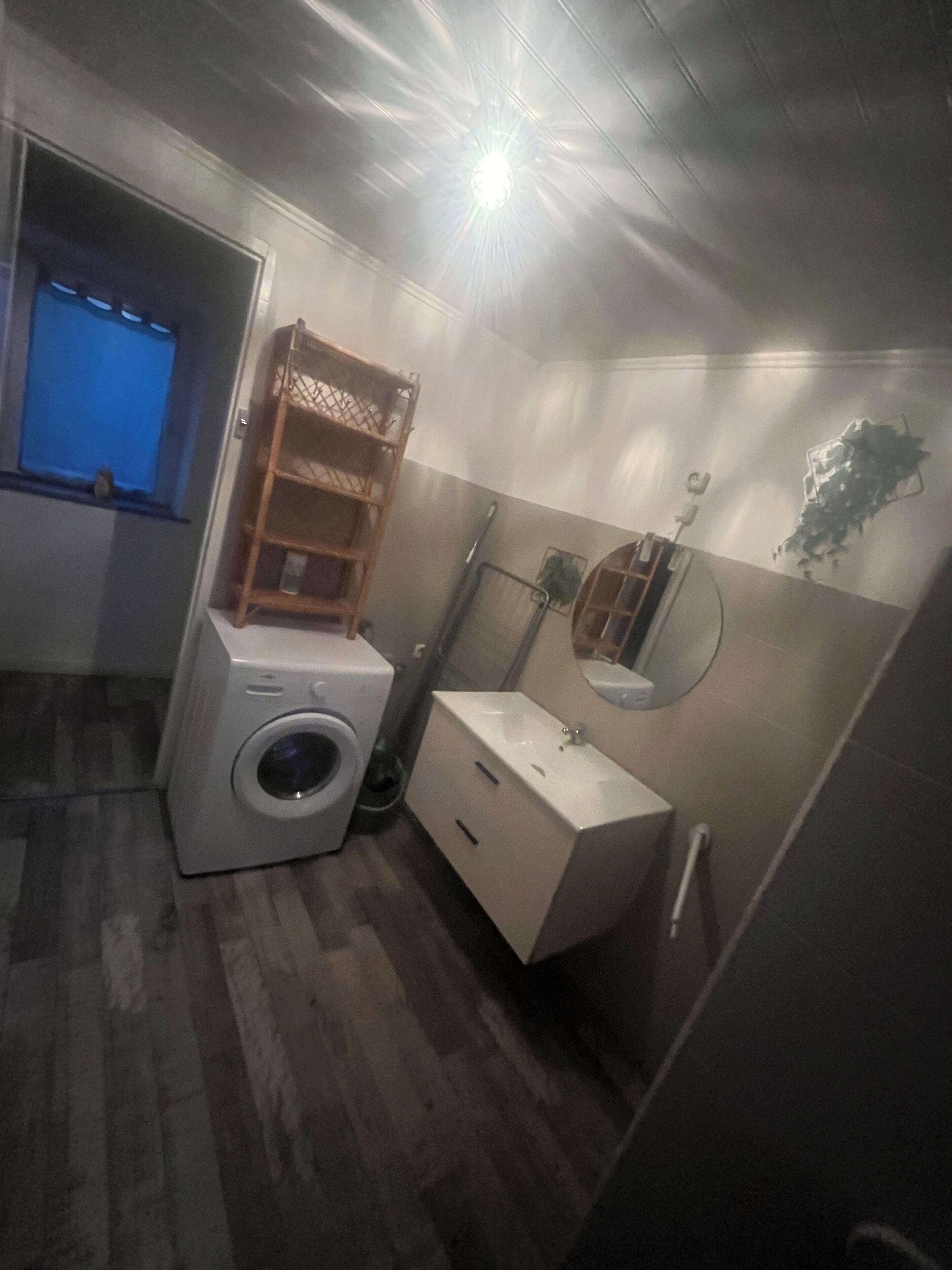 Een kleine badkamer met een wasmachine, een wastafel en een spiegel.