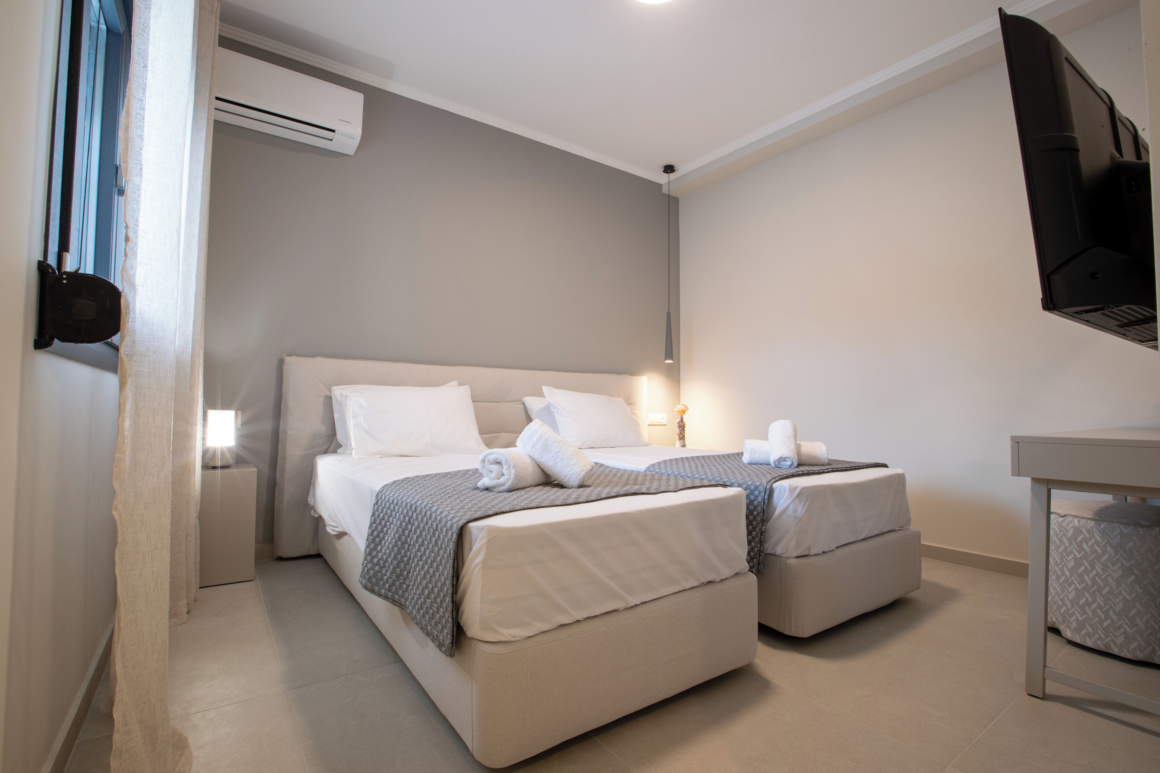 Une chambre d’hôtel avec deux lits, un téléviseur à écran plat et un système de climatisation.