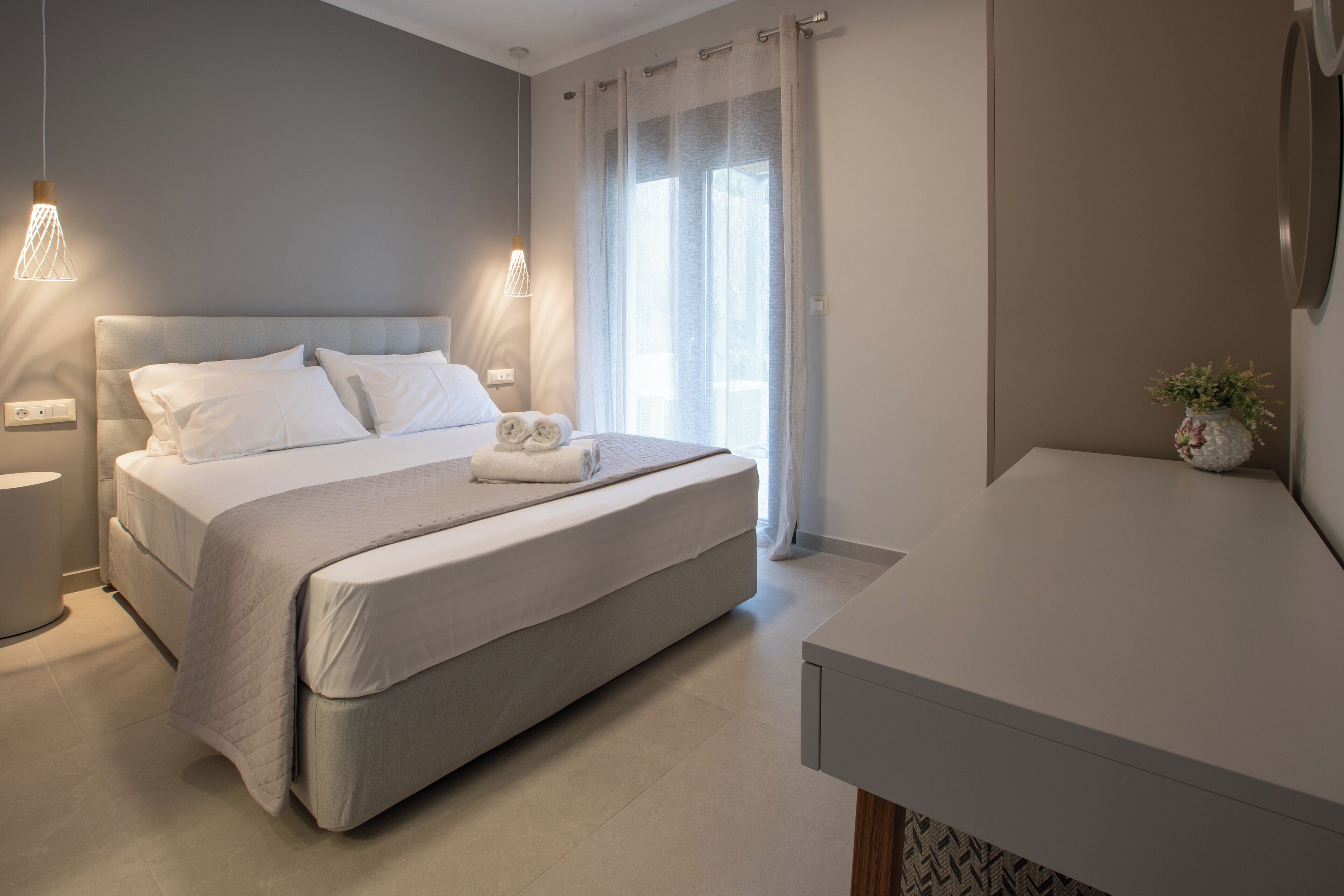 Une chambre à coucher moderne avec un grand lit, des lampes de chevet, une table de chevet et une fenêtre avec des rideaux.