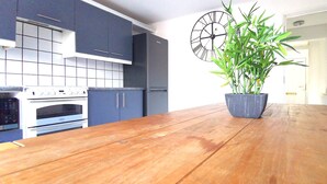 A kitchen with dark blue cabinets, a white stove, and a wooden table with a potted plant.