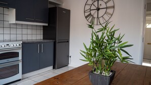 A kitchen with dark cabinets, a white oven, and a large clock on the wall.