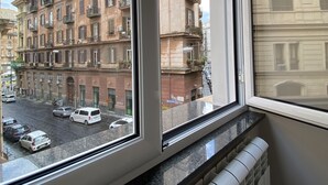 A view from a window overlooking a street with parked cars and multi-story buildings. - Porto Rooms & Suite (Naples)
