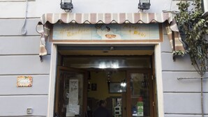 A restaurant entrance with a sign above the door and a small sign on the wall to the left. - Porto Rooms & Suite (Naples)