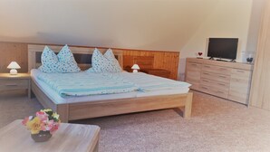 A bedroom with a wooden bed, two nightstands, a TV, and a dresser.