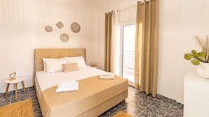 A hotel room with a large bed, a small bedside table, a potted plant, and a view of the outside. - Skioni Apartments (Kassandra)
