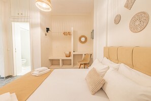 A hotel room with a bed, a desk, a chair, and a bathroom visible through an open door. - Skioni Apartments (Kassandra)