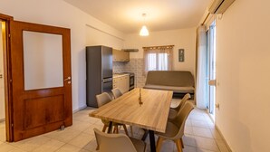 A compact kitchen with a dining table, chairs, and a sofa. - Skioni Apartments (Kassandra)