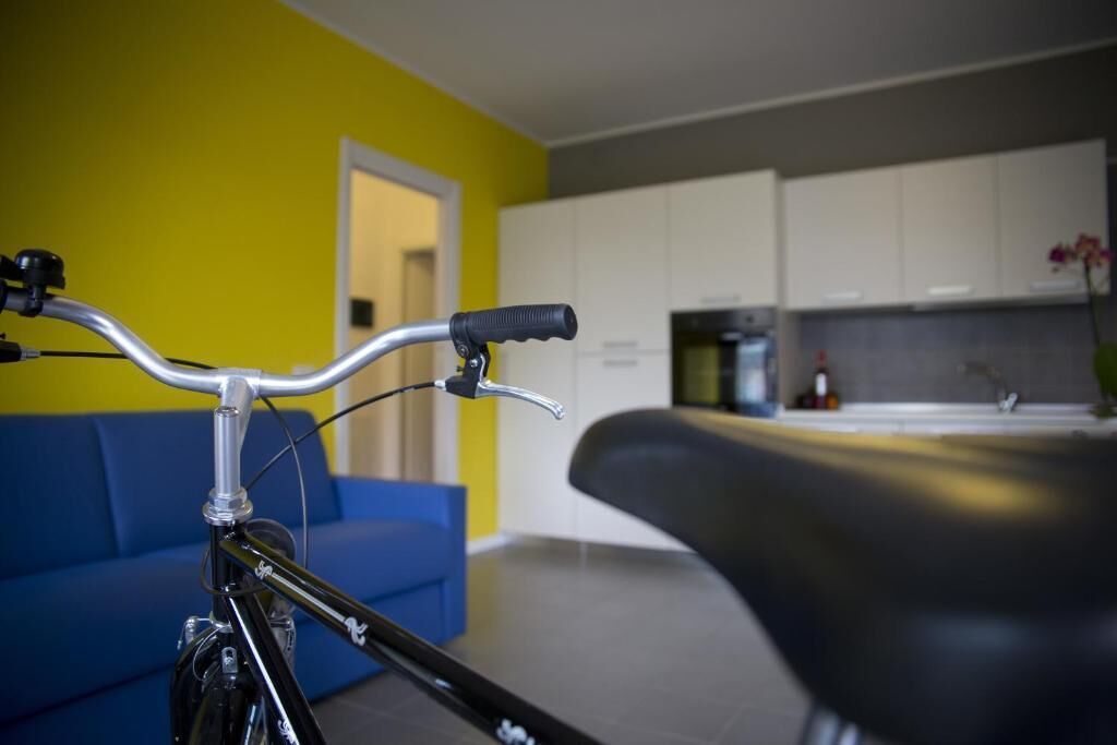 Une cuisine moderne avec des meubles blancs, un plan de travail noir et un mur jaune.