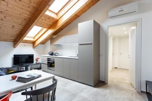 A modern kitchen with skylights, a dining area with a table and chairs, and a TV.