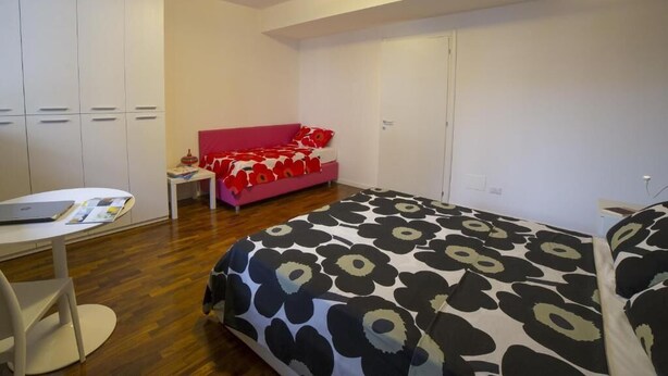Quarto com cama, escrivaninha, cadeira, guarda-roupa e sofá rosa.