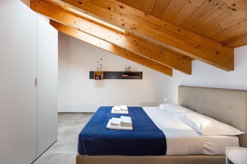 A bedroom with a bed, a bedside table, a wardrobe, and a wooden ceiling structure.
