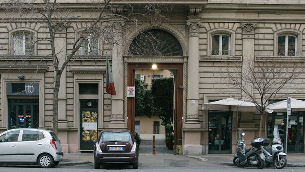 A multi-story building with a classic architectural style, featuring a central entrance with an archway, multiple windows with shutters, and balconies. - Vatican Garden Rooms (Rome)