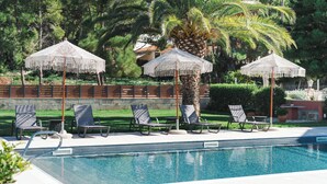 A pool area with lounge chairs and white patterned umbrellas. - Anthoula's House (Kefalonia)