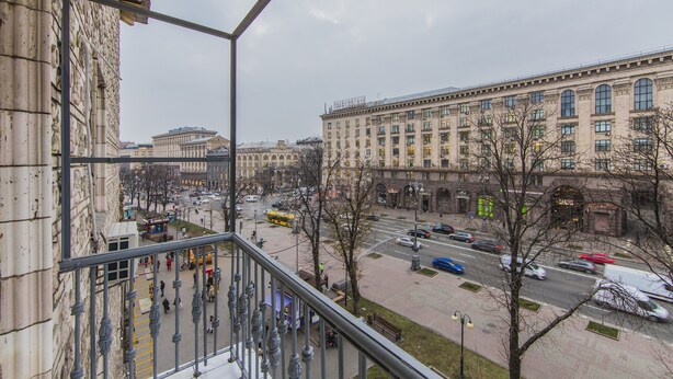 Vista da un balcone su una strada cittadina con palazzi, un tram e pedoni.