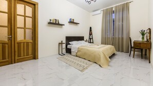 Una camera da letto con un letto, comodini, una scrivania, una sedia, un armadio, un lampadario e una finestra con tende.