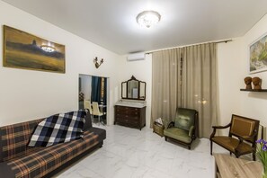 Una sala de estar con un sofá, una silla, una mesa de madera, un espejo y un cuadro en la pared.