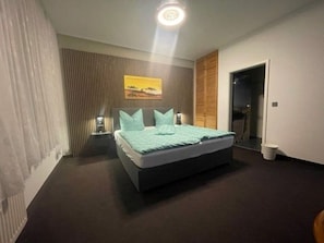 A bedroom with a bed, bedside tables, a wall-mounted artwork, a door, and a light fixture. - Holiday apartment - private room at the Ginkgo tree (Erfurt)