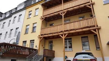 Ein mehrstöckiges Gebäude mit Balkonen, einer Treppe und einem parkenden Auto.