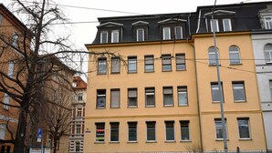 A multi-story building with a yellow facade, multiple windows, and a visible sign indicating a parking area. - Holiday apartment - private room at the Ginkgo tree (Erfurt)