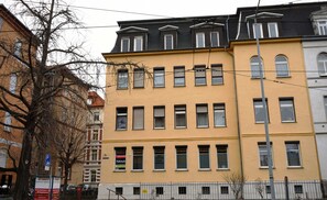 A multi-story building with a yellow facade, multiple windows, and a visible sign indicating a parking area. - Holiday apartment - private room at the Ginkgo tree (Erfurt)