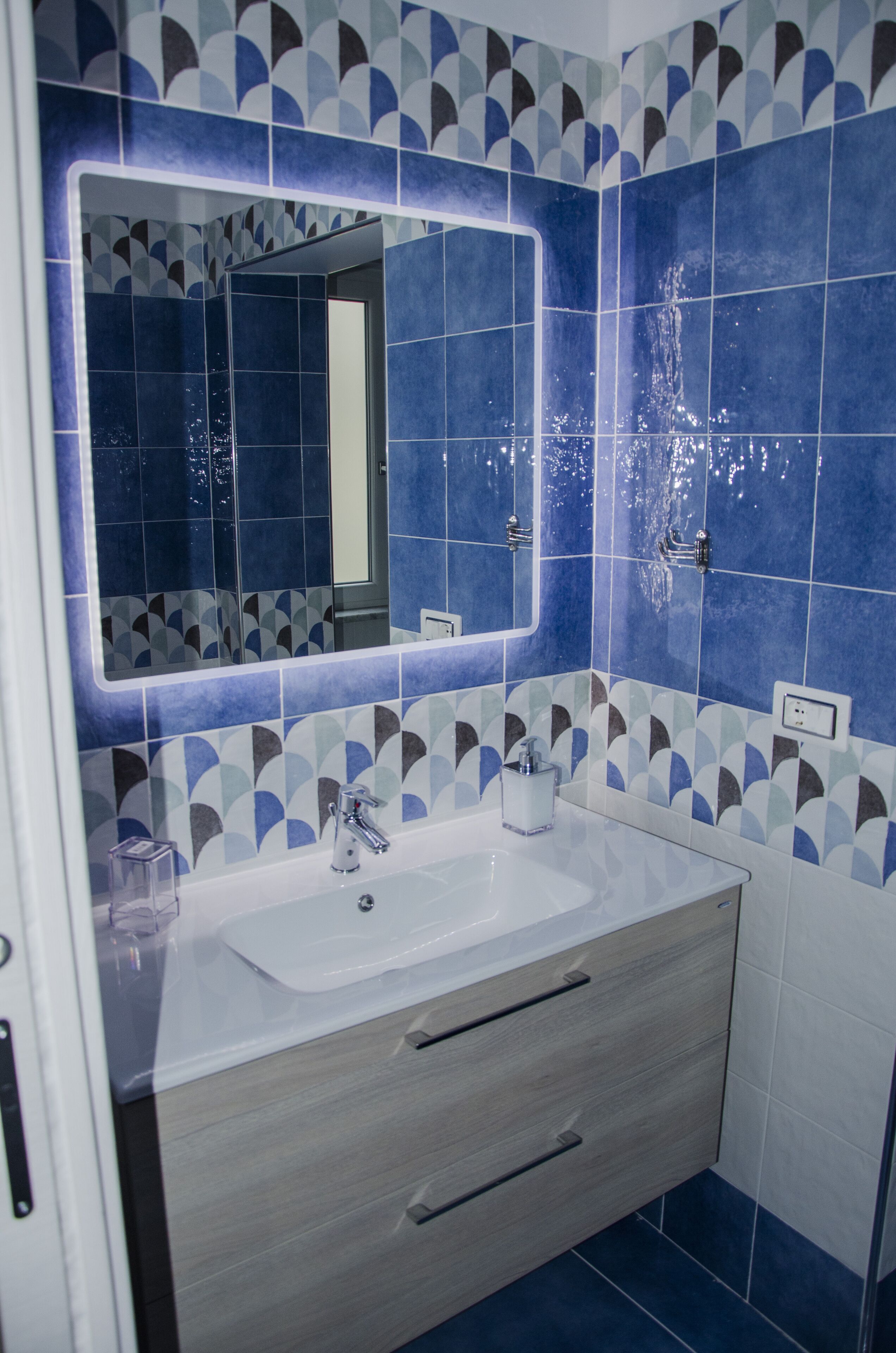 A bathroom with a white sink, a mirror, and blue and white patterned tiles.