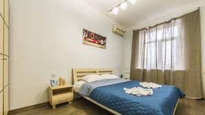 Ein Schlafzimmer mit einem Bett, Nachttischen, einem Schminktisch, einem Gemälde und einem Fenster mit Vorhängen.