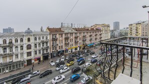 Eine belebte Innenstadtstraße mit historischen Gebäuden, einem Fußgängerweg und einem Parkplatz.
