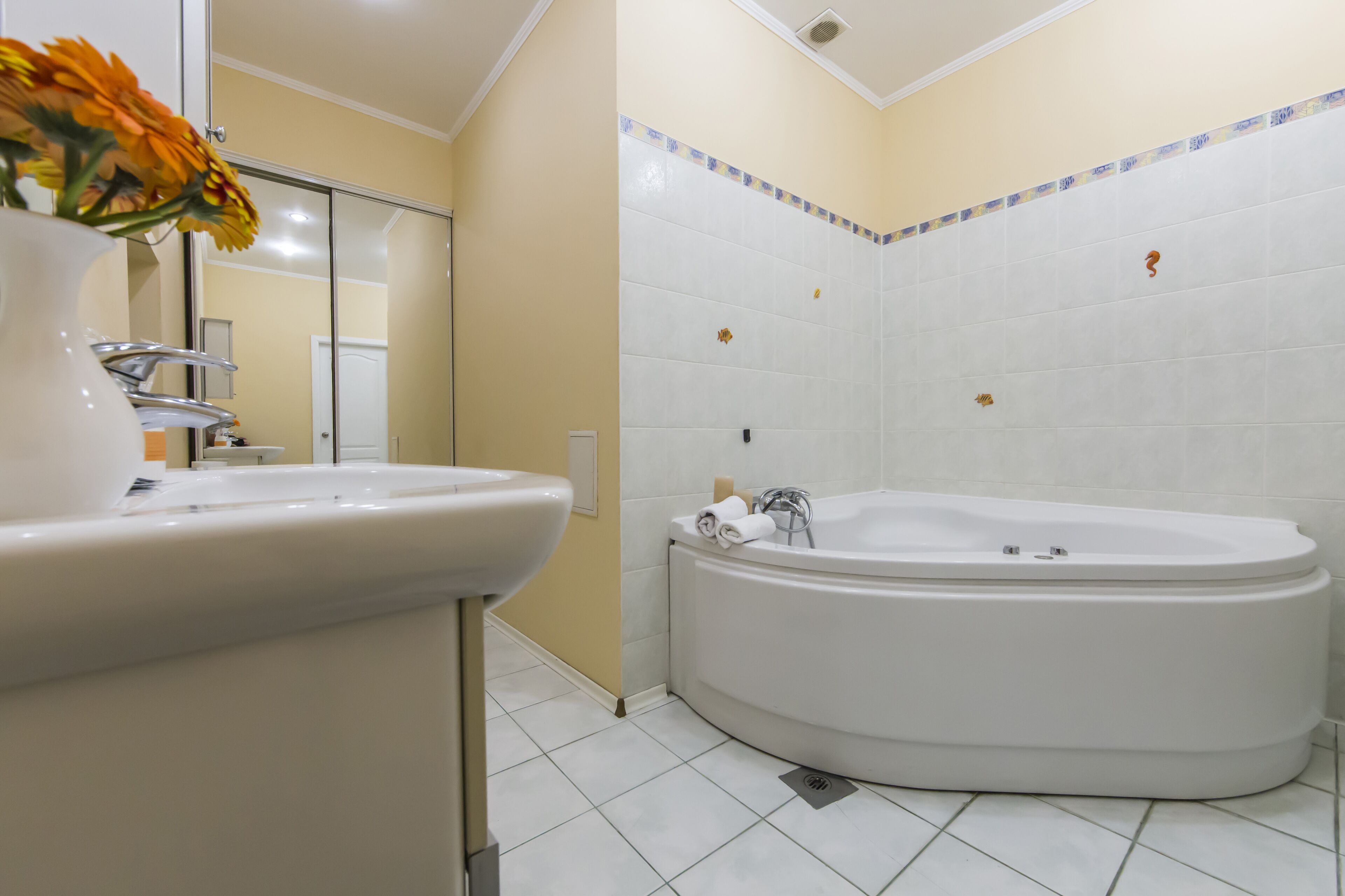 A modern bathroom with a white sink, a large bathtub, and a mirror.
