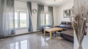 Un salon moderne avec un canapé, une table basse et une vue sur l’extérieur grâce à de grandes fenêtres.