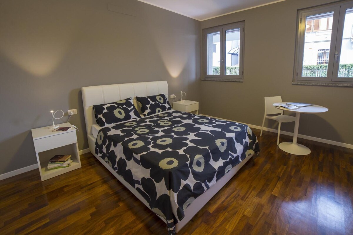 Een slaapkamer met een bed, nachtkastjes, een stoel en een raam.