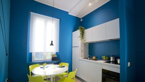 Una cucina moderna con pareti blu, mobili bianchi e un tavolo da pranzo rotondo con sedie gialle.