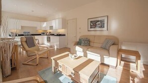 A modern living room with a sofa, a coffee table, and a dining area with chairs. - Carlton Lodge | Classic Seaside Charm | Parking (Broadstairs)