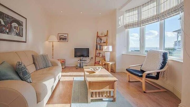 A living room with a sofa, a coffee table, a chair, a TV, and a bookshelf. - Carlton Lodge | Classic Seaside Charm | Parking (Broadstairs)