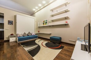 A modern living room with a sofa, ottoman, and a flat-screen TV. - Gorgeous Cozy Apartment at Horodetskogo (Kyiv)
