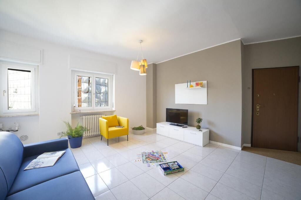 Un salon moderne avec un canapé, un fauteuil jaune, un téléviseur et une porte.