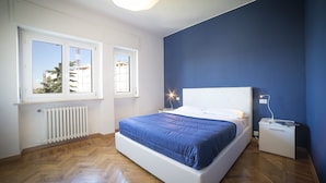 A bedroom with a large bed, a nightstand, a window, and a radiator. - Aurum ApartHotels Gambara (Milan)