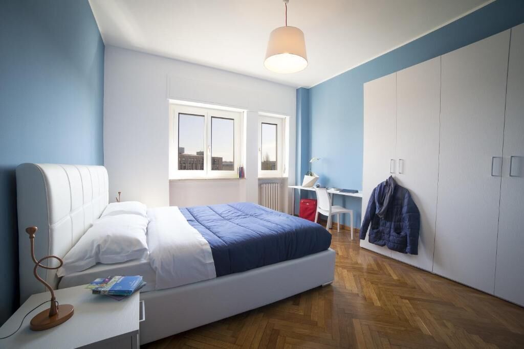 Un dormitorio con cama, escritorio, silla, radiador y armario.