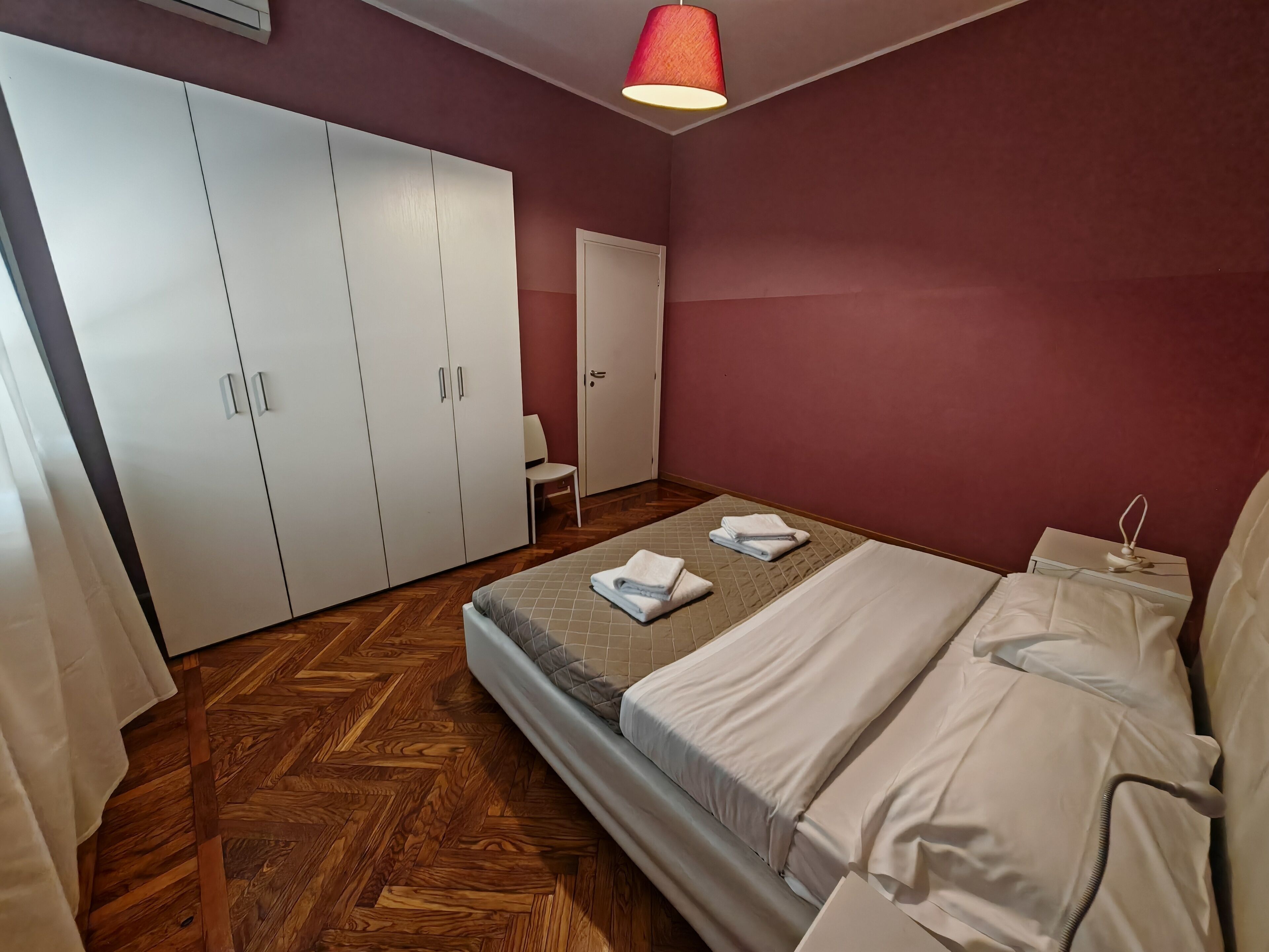 Un dormitorio con cama, armario y una silla.