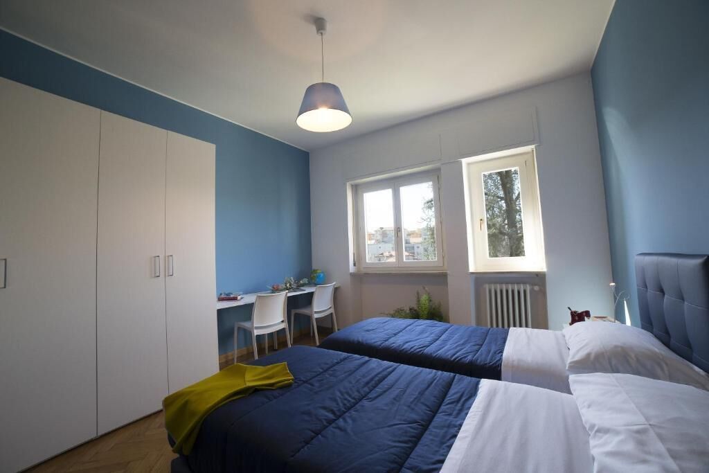 Un dormitorio con dos camas, un escritorio y una ventana.