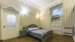 A bedroom with a wooden floor, a bed with a headboard, a nightstand, a dresser, and a wardrobe. - Stylish Apartment Close ot the Opera (Kyiv)